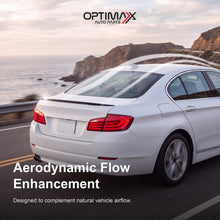 Gloss black trunk lip spoiler on white BMW 5 Series F10 sedan aerodynamic flow enhancement on coastal road
