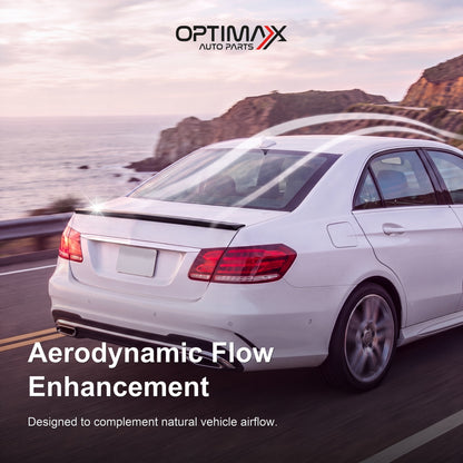 Gloss black trunk lip spoiler on white Mercedes-Benz E-Class W212 sedan aerodynamic flow enhancement on coastal road
