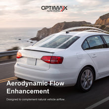 Gloss black trunk lip spoiler on white Volkswagen Jetta MK6 sedan aerodynamic flow enhancement on coastal road